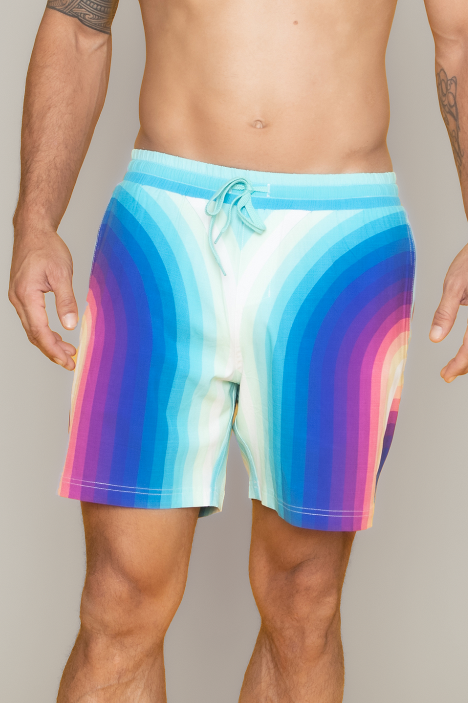 a man wearing a rainbow colored swim trunks